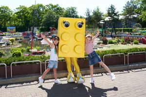 zwei Kinder im LEGOLAND mit großer LEGO Stein Figur in Farbe gelb
