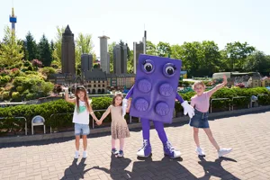Kinder im LEGOLAND mit großer LEGO Stein Figur in Farbe lila