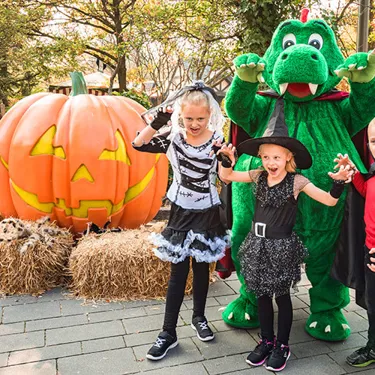 Parkdrache Olli mit verkleideten Kindern an Halloween im LEGOLAND Deutschland