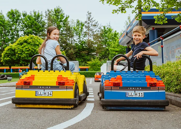 Dwoje dzieci prowadzi samochody w szkole jazdy LEGOLAND