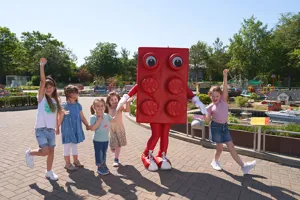 Kinder im LEGOLAND mit großer LEGO Stein Figur in Farbe rot